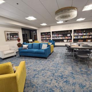 A vibrant and modern library interior featuring colorful couches and a well-stocked bookshelf.