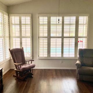 A cozy and inviting living room featuring a rocking chair and an armchair by the sunlit windows.