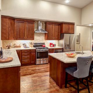 A modern kitchen featuring wooden cabinets, a central island, and stainless steel appliances.