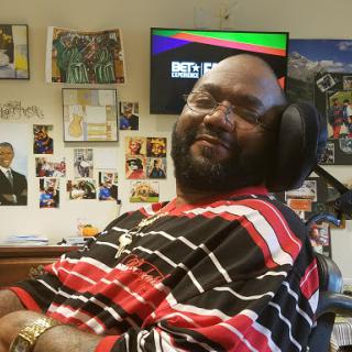 A joyful moment captured of a man in a wheelchair, surrounded by photos and memorabilia.