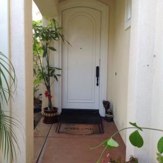 A welcoming front porch with potted plants leading to a white door.