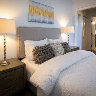 A modern bedroom with a comfortable bed adorned with fluffy pillows and warm lighting from bedside lamps.