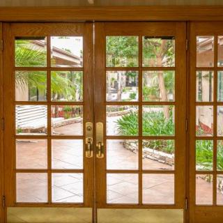 Wooden-framed glass doors with a view of a garden and patio.
