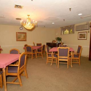 A cozy dining room featuring multiple tables and chairs, with a chandelier providing warm lighting.