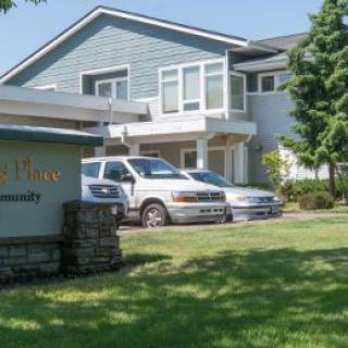 Residential building with cars parked in front and a sign on the lawn.