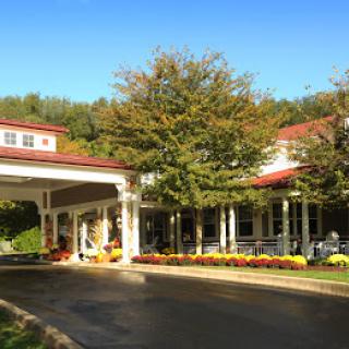 A charming entrance to a building surrounded by lush trees and autumn foliage.