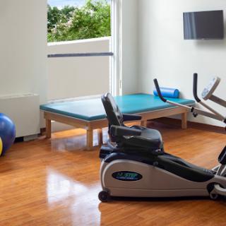 A well-equipped home gym featuring an elliptical machine, exercise ball, and rehabilitation table.