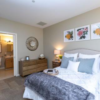 A well-decorated bedroom with a cozy bed, stylish artwork, and soft lighting.