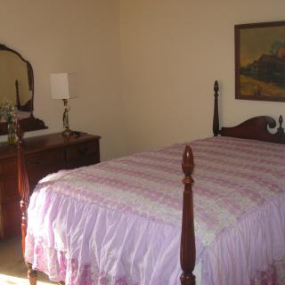 A cozy bedroom with a four-poster bed, dresser, and mirror.