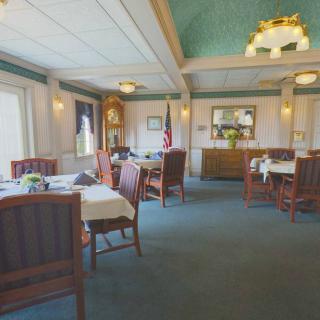An elegant dining room with neatly arranged tables and chairs, featuring large windows and classic decor.