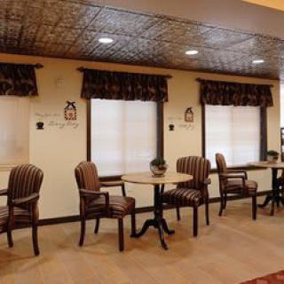 A cozy seating area with tables and chairs, complemented by window curtains and decorative ceiling.