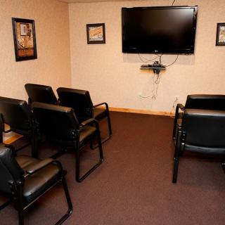 A small waiting room with chairs arranged in front of a wall-mounted television.