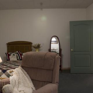 A cozy bedroom with a bed, chair, and mirror.