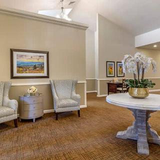 A cozy lobby interior featuring elegant seating, artwork on the walls, and a decorative plant on a central table.