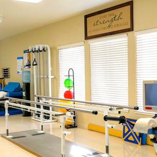 A well-equipped physical therapy room featuring parallel bars and various rehabilitation tools.