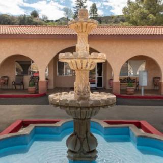 A decorative fountain situated in a courtyard with archways and a tiled roof.