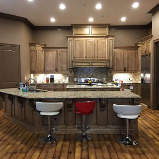 A modern kitchen with wooden cabinets, a granite countertop island, and bar stools.