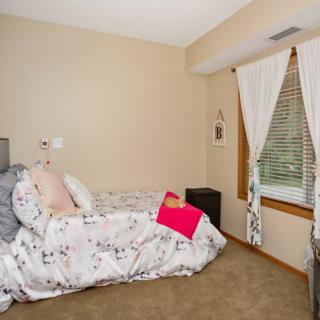 A cozy bedroom with a bed next to a window adorned with white curtains.