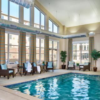 A luxurious indoor swimming pool with ample seating and natural light streaming through large windows.