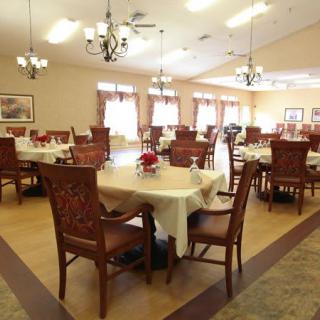 A spacious dining room with elegantly set tables and chandeliers.