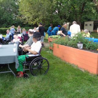 A community gathering in a garden setting with various attendees enjoying the event.
