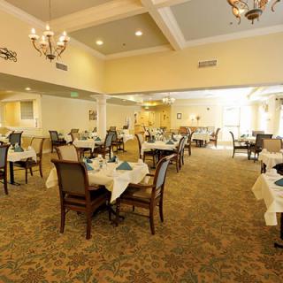 An elegant dining room setup with neatly arranged tables and chairs, adorned with chandeliers.