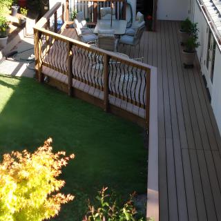 A backyard featuring a wooden deck with patio furniture and surrounding greenery.