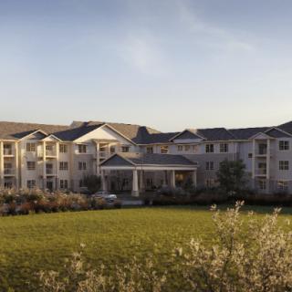 A large residential building with a well-maintained lawn and a clear sky at sunset.