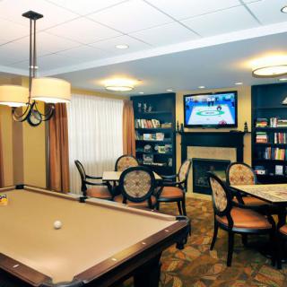 A cozy game room featuring a pool table, television, and comfortable seating around a fireplace.