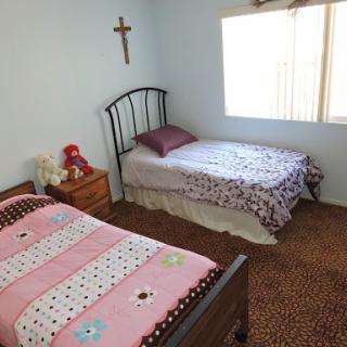 A cozy children's bedroom featuring two beds, decorated with playful bedding, and a cross on the wall.