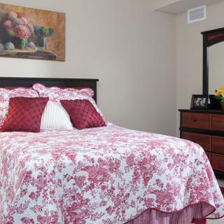 A cozy bedroom with floral bedding and a matching dresser set.