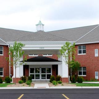 A brick building with a prominent entrance and surrounding greenery.