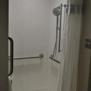 An accessible shower with handrails and a curtain.