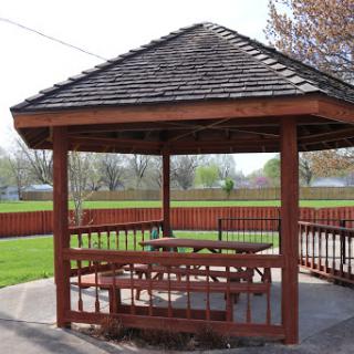 A spacious wooden gazebo in a park, perfect for gatherings and enjoying the outdoors.