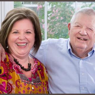 An older couple smiling and embracing each other indoors.