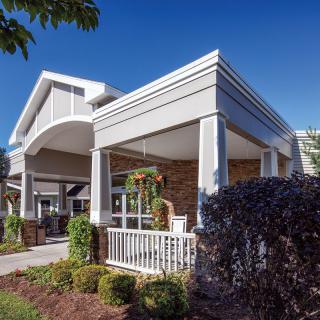 A modern residential building with a porch and landscaped surroundings.