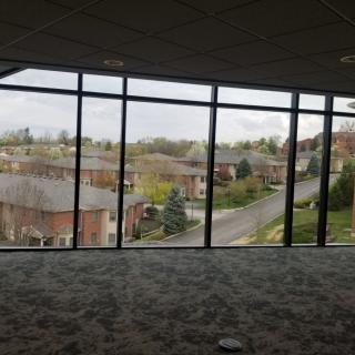 A large panoramic window provides a view of a suburban residential area on an overcast day.