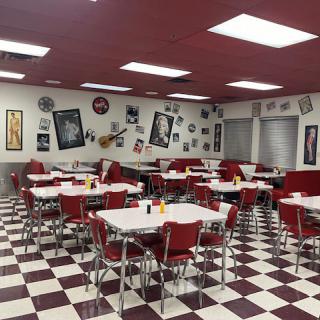 A retro-style diner with red chairs and checkered flooring, decorated in a vintage 1950s theme.