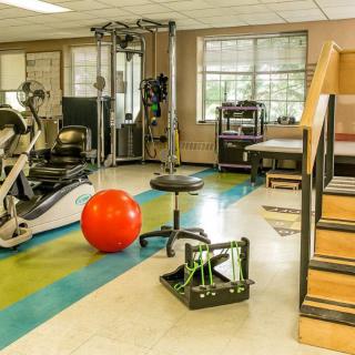 A fitness and rehabilitation area equipped with various exercise machines and therapy tools.