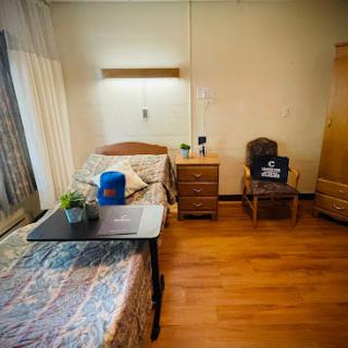 A cozy hospital room featuring a bed, nightstand, and various pieces of furniture.