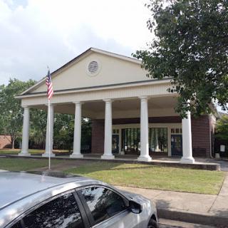 A classical-style public building with tall columns and an American flag.
