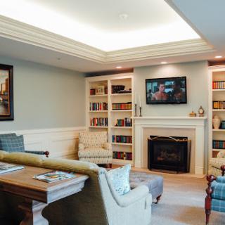 A cozy and modern living room featuring bookshelves, a fireplace, and a mounted TV.