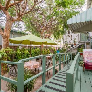 A charming outdoor patio area with tables, chairs, and green umbrellas surrounded by lush trees.
