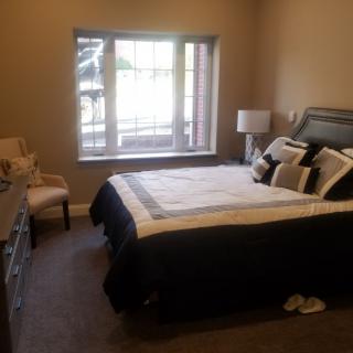 A cozy bedroom with a neatly made bed and large window.