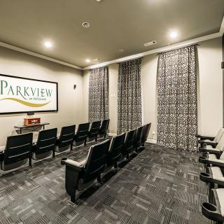 A small theater room with rows of seating facing a projector screen.