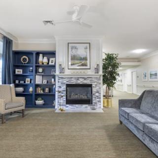 A cozy living room featuring a fireplace, bookshelf, sofa, and armchair with elegant interior design.