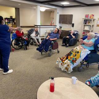 Residents participate in a group activity led by a staff member at a nursing home.