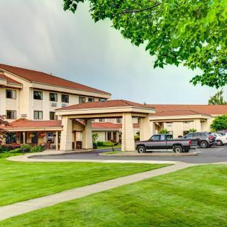 A hotel with a well-maintained exterior, featuring a parking lot and landscaped surroundings.