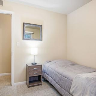 A minimalist bedroom with a single bed, nightstand, and lamp.