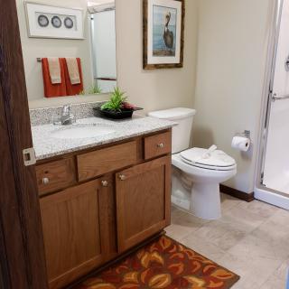 A neatly organized bathroom with a wooden vanity, mirror, toilet, and shower area.